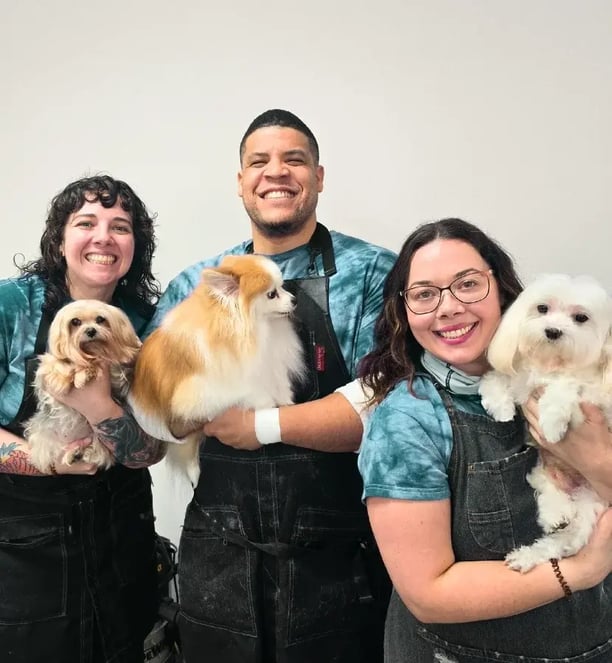 Dog groomers Amanda, Aaron, and Anna posing with pups