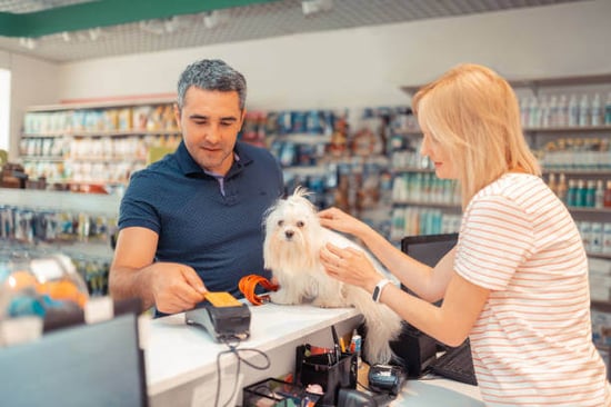 A man taps a credit card on a payment terminal in a pet store