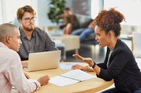 A group of three people talk together