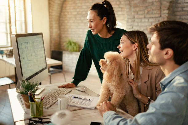 people at desk looking at desktop computer with dog