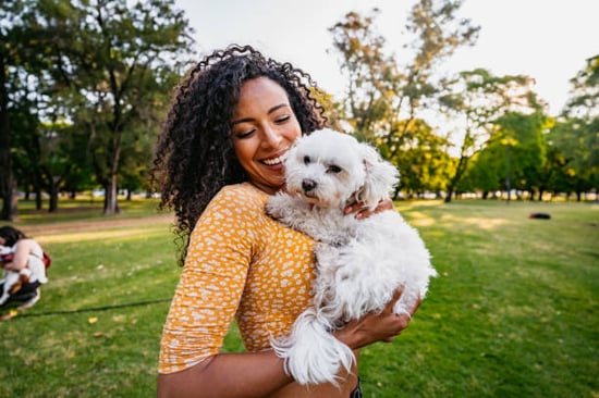 A woman holds a dog outside