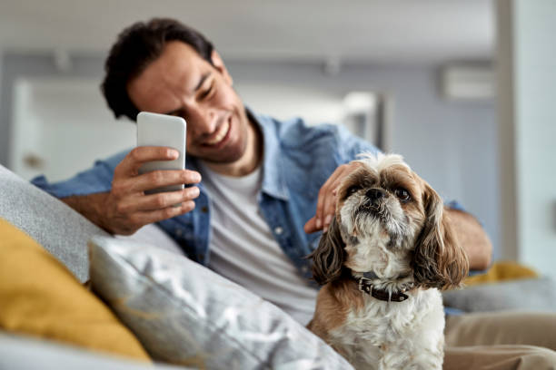 A man uses a phone while his dog sits next to him