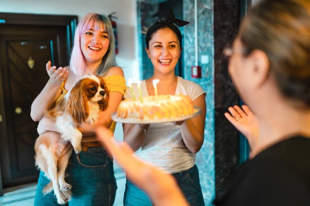 two pet lovers greeting a client with her dog and a cake