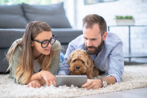 Two people look at an ipad as a dog sits between them