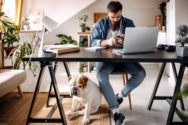 A man uses a phone while a dog sits at his feet