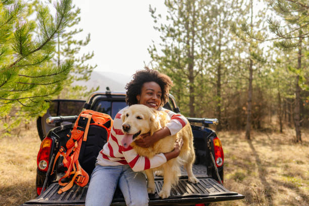 A woman hugs her dog outside as they sit on the bed of a truck outside