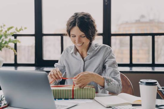 A woman wraps a holiday present at an office