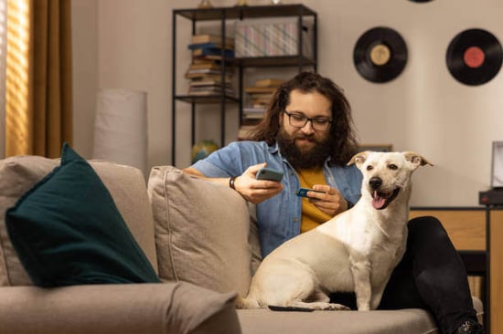 A person holds a phone and credit card while a dog sits next to them