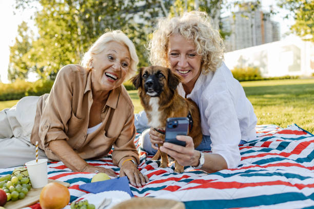 two women outside taking a selfie with their dog 
