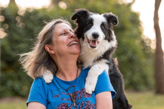 A woman poses with a dog outside