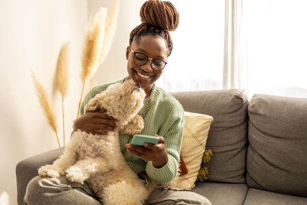 A woman uses her phone while holding a dog