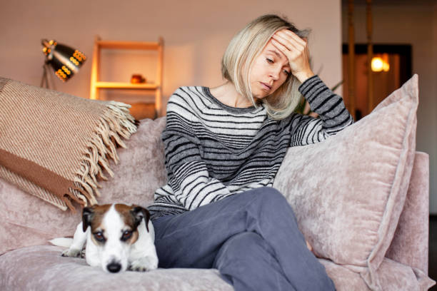 stressed and burnt-out pet-care worker on couch with sad dog