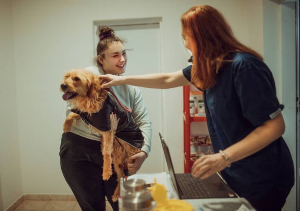 pet parent and staff member smiling with dog during pickup