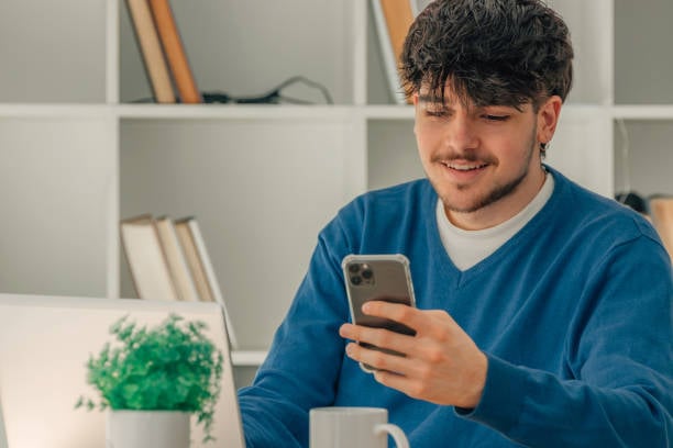 young man at work receiving a text update about his pet