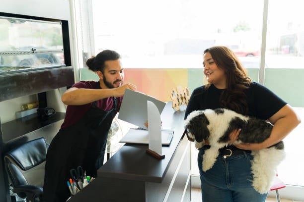 dog groomer with tablet showing membership details to woman with dog