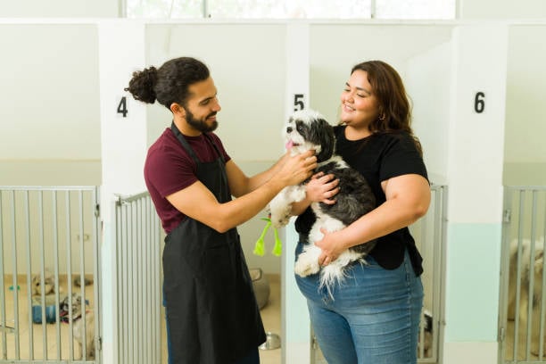 a pet parent and kennel owner smiling with a dog at a peaceful dog boarding facility