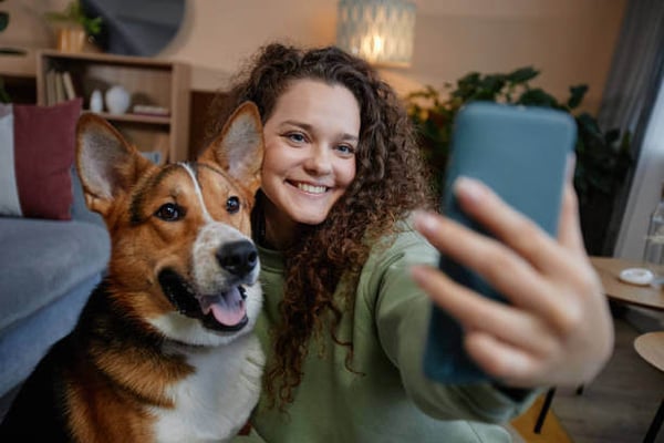 A woman takes a phone selfie with a dog