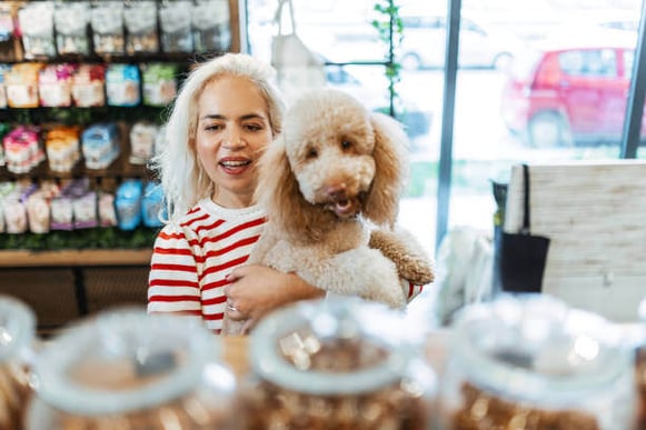 A woman holds her dog inside a pet store