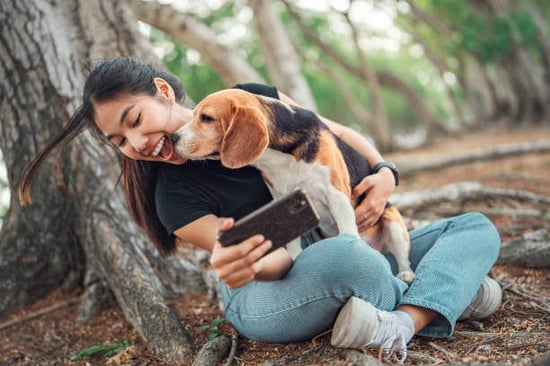 A woman takes a selfie with a dog outside