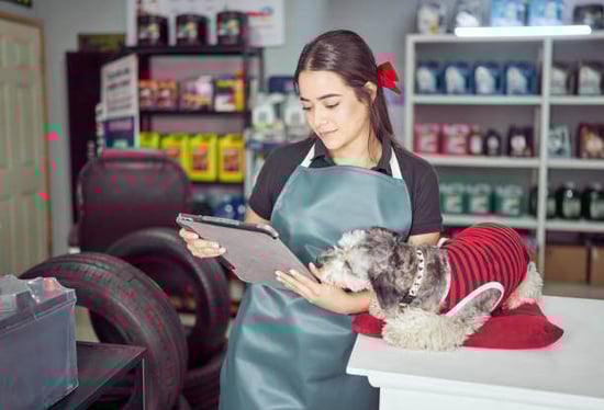 A woman uses a tablet as a dog sits next to her