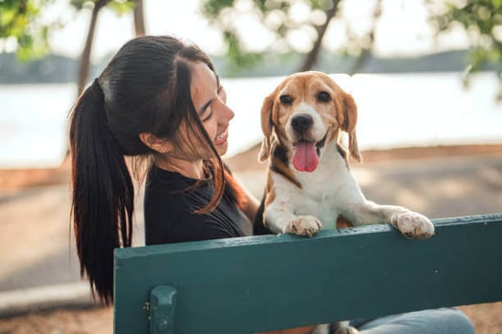 A woman smiles at her dog outside