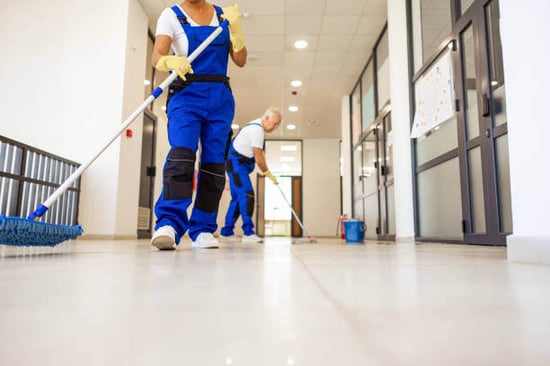 Two people clean the floor at a business