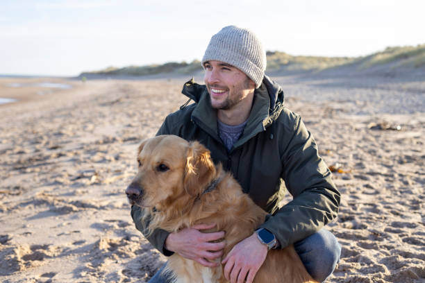 A man hugs his dog on the beach