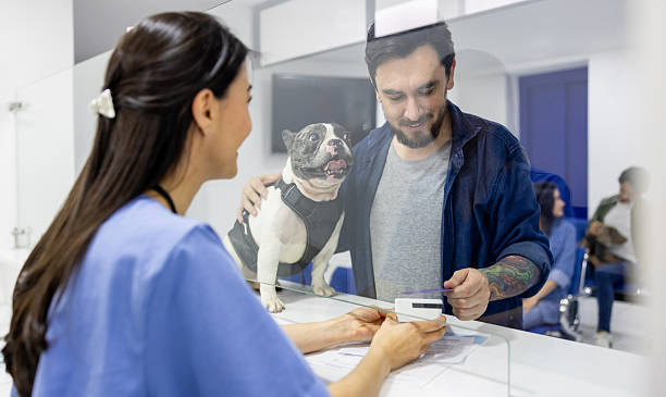 man with dog paying for pet care at credit card terminal
