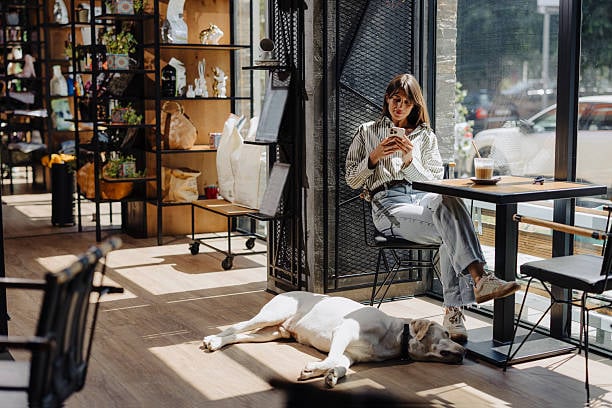 woman texting on phone with dog sleeping at her feet