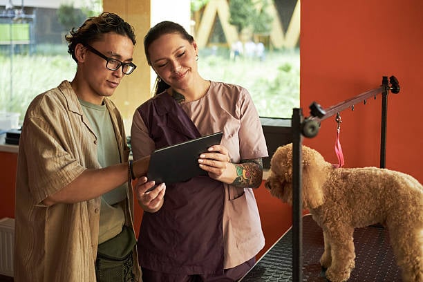 dog groomer showing new clients website and app on tablet