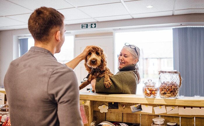 older woman pet parent with cockapoo getting pet-care services for a discount