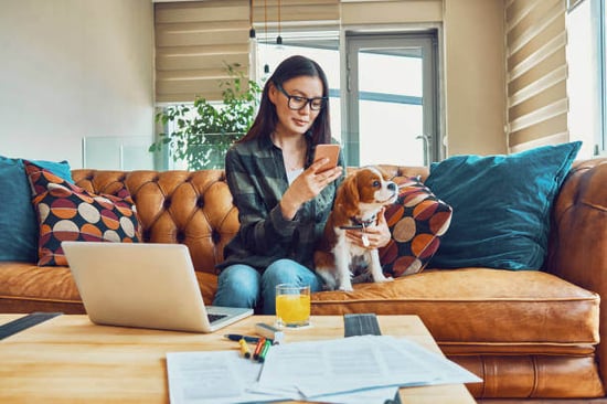 A woman uses a phone while sitting next to her dog